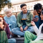 group of young adults sitting together and talking outdoors